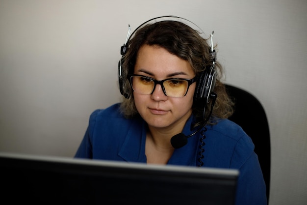 Un serio operatore di call center sta parlando con un cliente mentre guarda lo schermo di un computer in primo piano