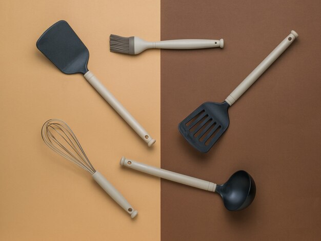 Un set di accessori da cucina su uno sfondo bicolore. Utensili da cucina in plastica. Disposizione piatta.