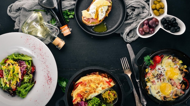 Un set di cibo Frittata Shakshuka sandwich con insalata di avocado con uovo in camicia su sfondo di legno Spazio libero per il testo Vista dall'alto