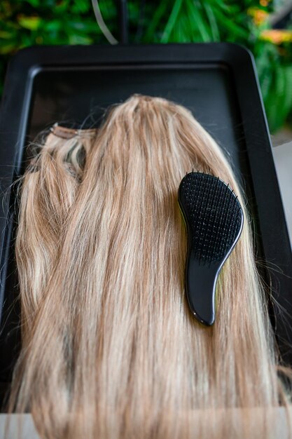 Un set di diversi strumenti per l'estensione dei capelli per una donna bionda in un salone di bellezza