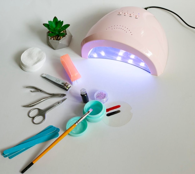 Un set di forbici per strumenti per manicure per un taglio di capelli e uno spingi cuticole e una lampada UV per asciugare la gommalacca sulle unghie