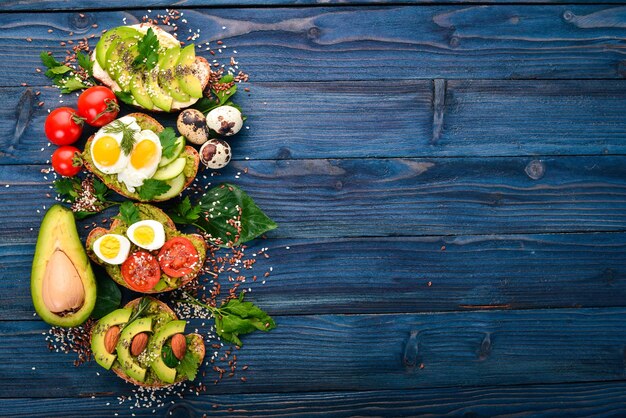 Un set di panini con avocado pomodorini e uova di quaglia e semi di chia su uno sfondo di legno Vista dall'alto Spazio libero per il testo