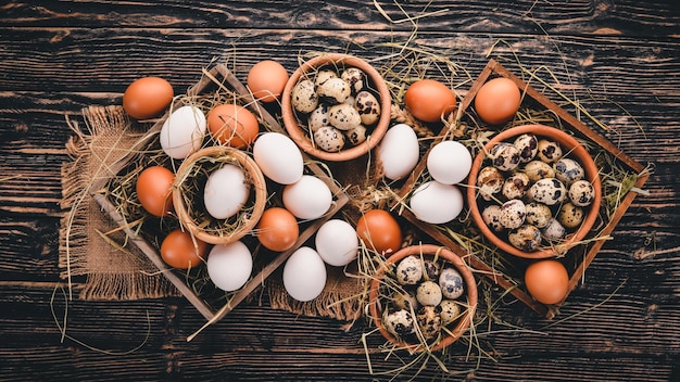 Un set di uova di gallina e quaglia su uno sfondo di legno Vista dall'alto Copia spazio