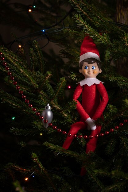 Un simpatico giocattolo di Natale siede su un abete sempreverde decorato con ghirlande e altri giocattoli di Capodanno