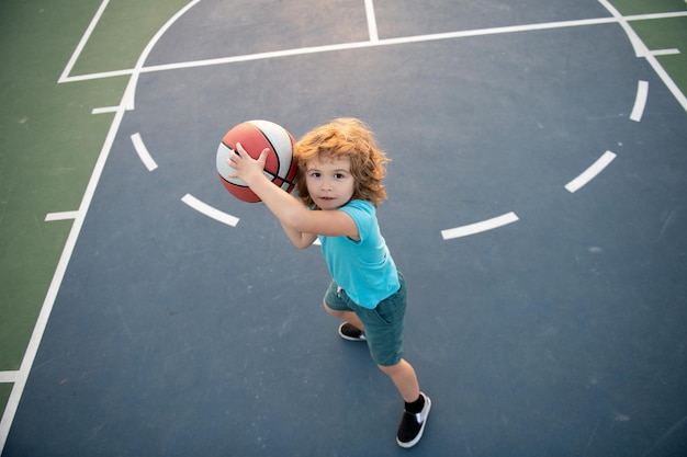 Un simpatico ragazzo sorridente gioca a basket con bambini attivi che si godono il gioco all'aperto con la vista dall'alto della palla da basket