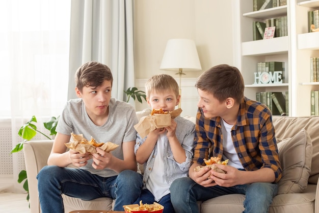 Un simpatico tre ragazzi adolescenti che mangiano fast food in soggiorno