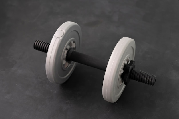 Un singolo manubrio di peso grigio, attrezzatura per body building sportiva isolata sullo sfondo a colori