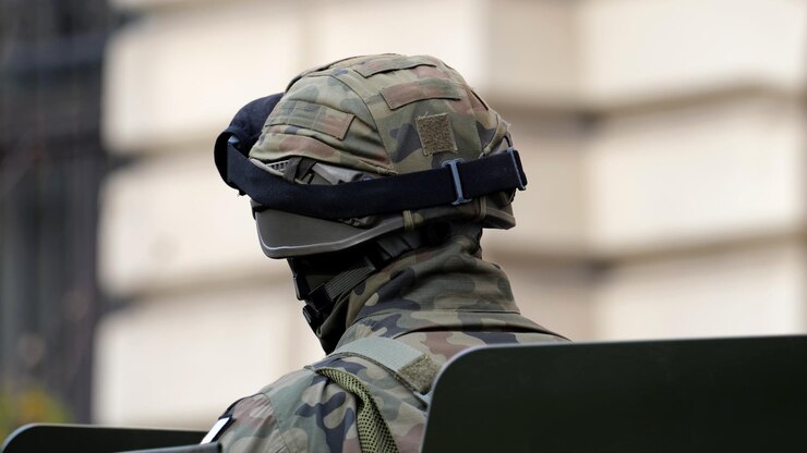 Un singolo soldato anonimo in uniforme di camuffamento verde generico, casco e occhiali di protezione