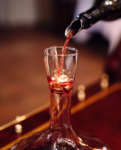 Un sommelier che versa il vino rosso nel decanter