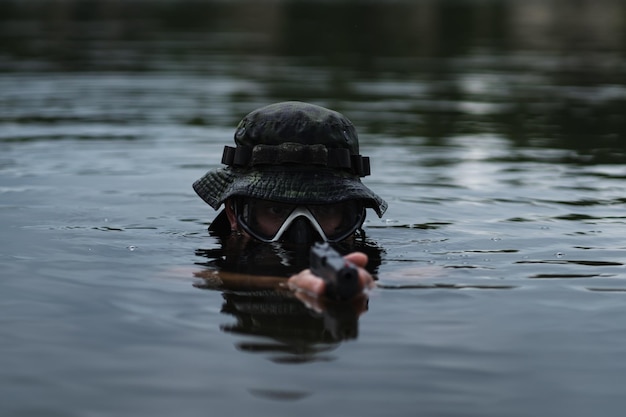 Un subacqueo da combattimento punta una pistola nell'acqua. Foto di primo piano Foto di alta qualità