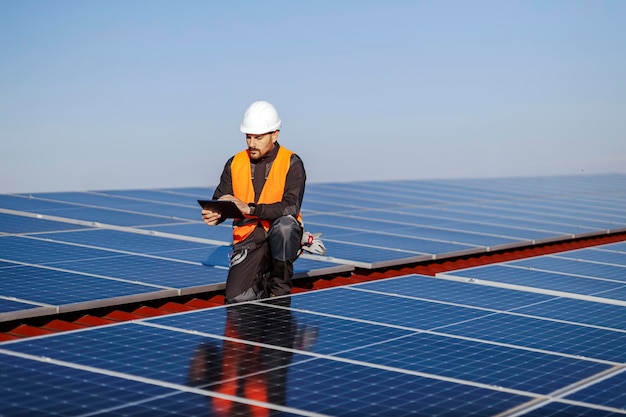 Un supervisore inginocchiato e controllando la correttezza dei pannelli solari sul tetto