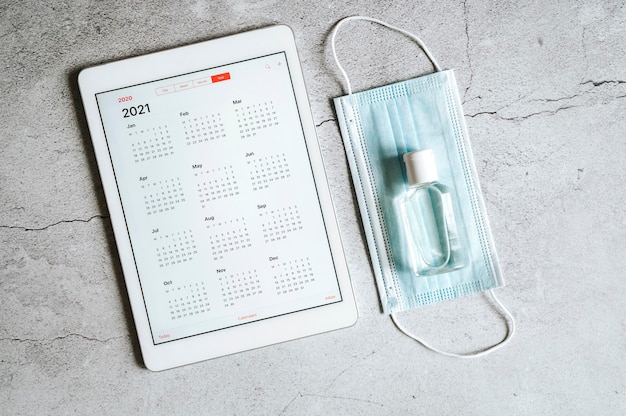 Un tablet con un calendario aperto per l'anno 2021 e una maschera medica protettiva