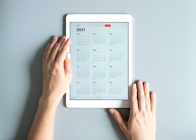 Un tablet con un calendario aperto per l'anno 2021 nelle mani di una donna