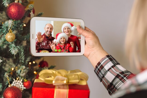 un tablet digitale tra le braccia e ascolta un saluto alla vigilia di Natale in videoconferenza