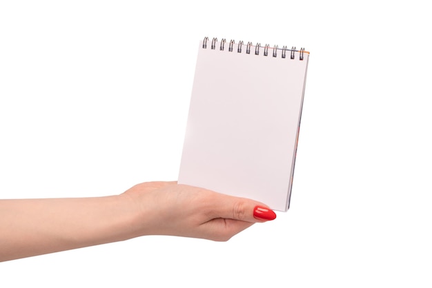 Un taccuino con carta bianca vuota nelle mani della donna con unghie rosse
