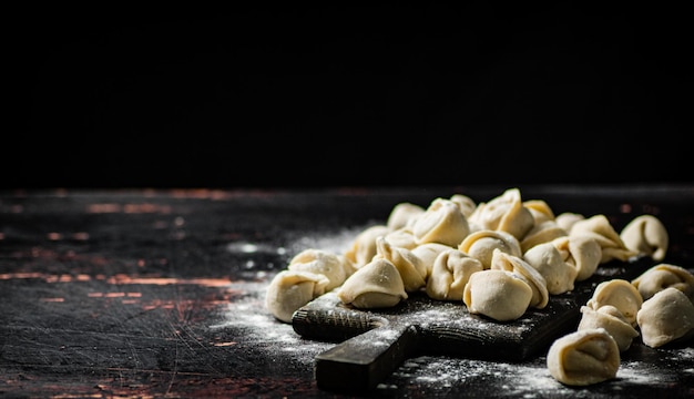 Un tagliere di legno con sopra degli gnocchi crudi