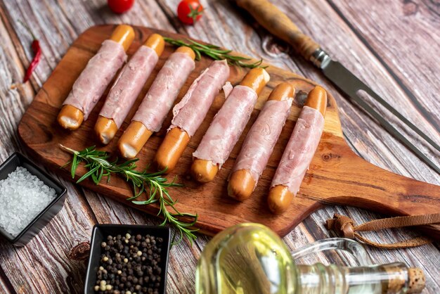 Un tagliere di legno con sopra delle salsicce e accanto un coltello.