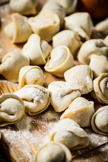 Un tagliere di legno con sopra una pila di ravioli fatti in casa.