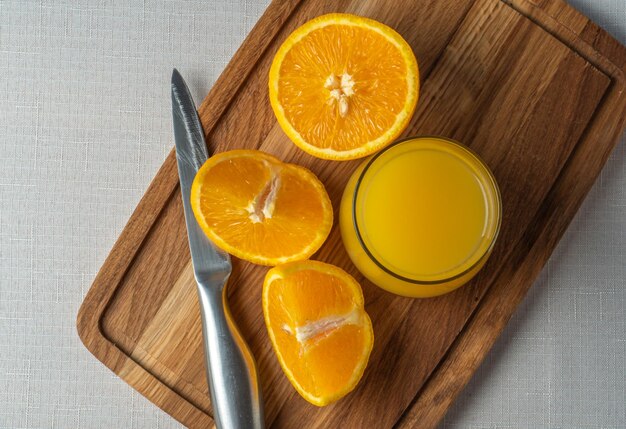 Un tagliere di legno con succo d'arancia e un bicchiere di succo d'arancia.