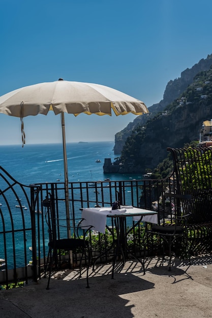 Un tavolo accogliente in un caffè con una tovaglia bianca con una splendida vista della città di Positano in Italia