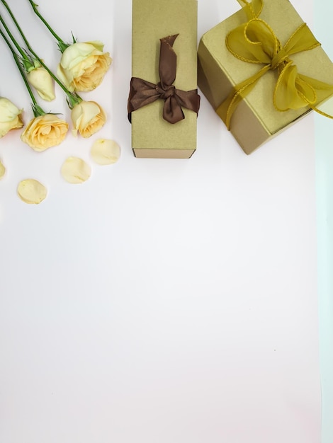 Un tavolo bianco con un mazzo di rose e una confezione regalo con un nastro d'oro.