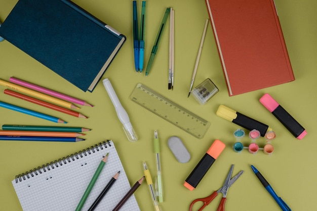 Un tavolo con quaderni, matite, forbici e rifornimenti scolastici