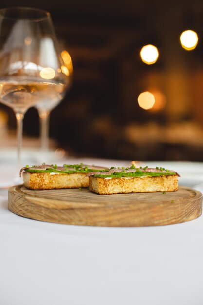 Un tavolo con sopra due piccoli panini con un bicchiere di vino in sottofondo.