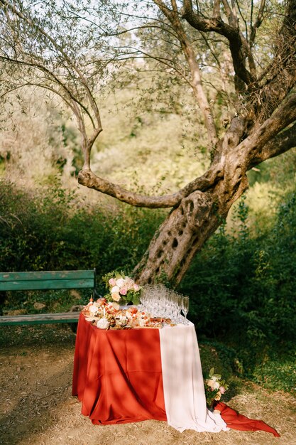 Un tavolo con un mantello rosso servito per un evento di matrimonio con banchine pulite vuote per champagne e a