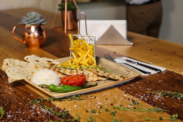 Un tavolo con un piatto di cibo e un bicchiere di patatine fritte