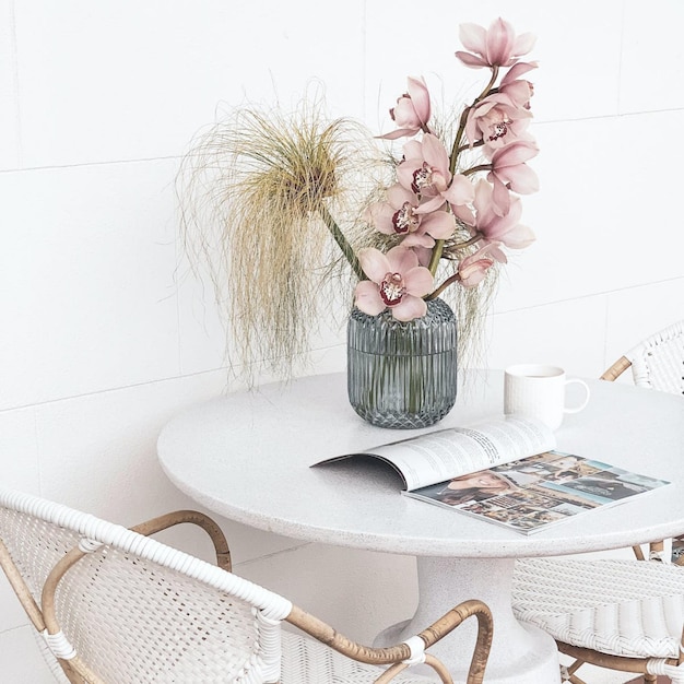 Un tavolo con un vaso di fiori e una rivista sopra