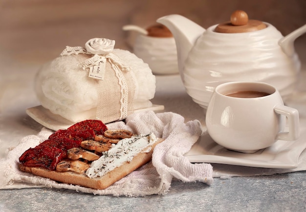 Un tavolo con una tazza di tè e un panino con formaggio e salse.