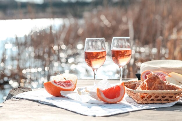 Un tavolo da picnic con due calici di vino e un cesto di frutta