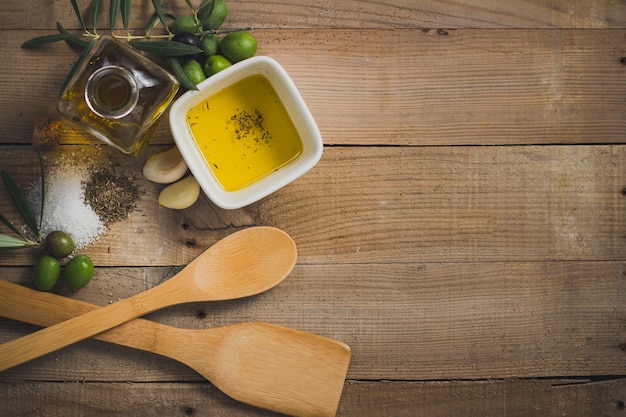 Un tavolo di legno con olio d'oliva e una ciotola di olio d'oliva.