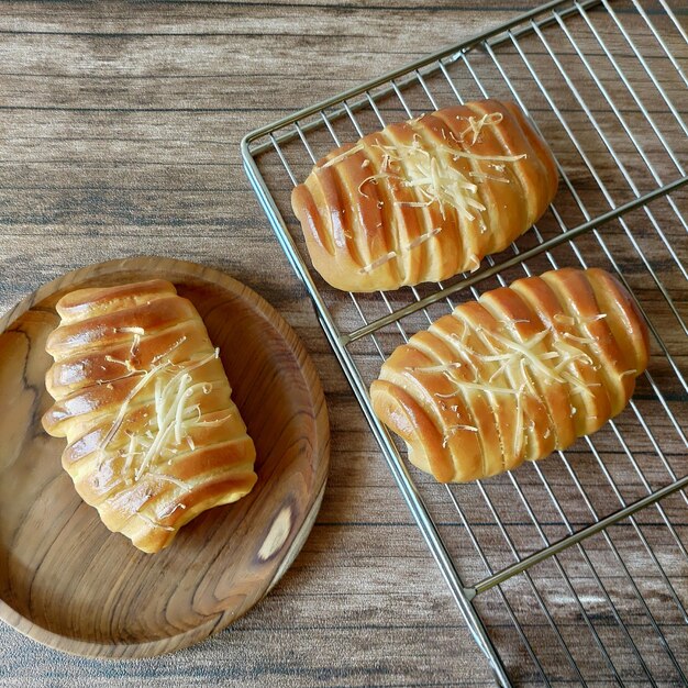 Un tavolo di legno con tre pani e uno con sopra del formaggio.