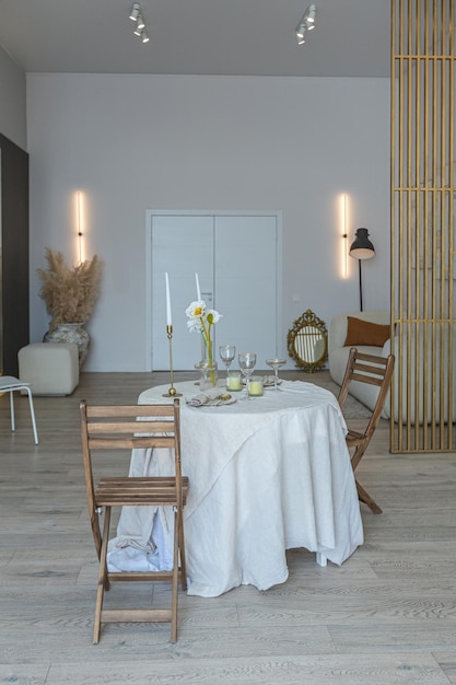 Un tavolo romantico è servito per due nella cucina in un luminoso appartamento a pianta aperta in stile moderno con pareti leggere e pavimenti in legno