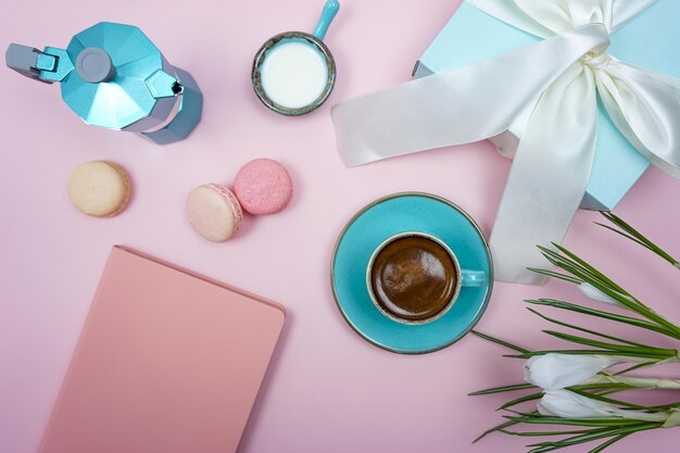 Un tavolo rosa con un laptop, una tazza di caffè, una tazza di caffè e un mazzo di fiori.