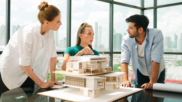 Un team di architetti intelligenti discute sulla progettazione della casa mentre un bel lavoratore presenta l'idea usando un portatile Un gruppo di ingegneri professionisti condivide la progettazione di brainstorming Design aziendale Tracery