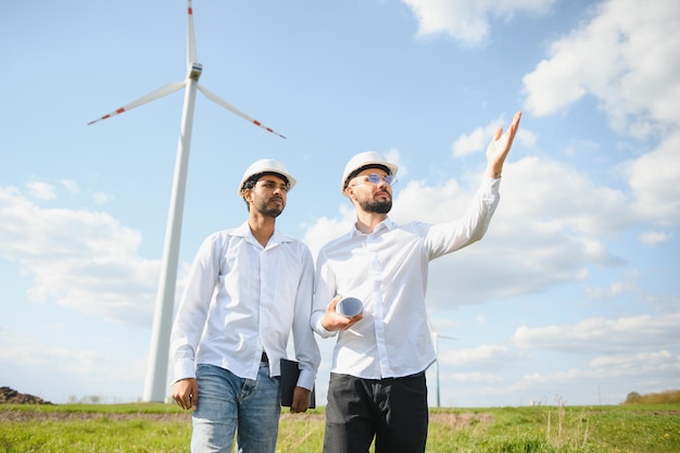 Un team di ingegneri maschi che lavorano insieme nella fattoria dei generatori di turbine eoliche