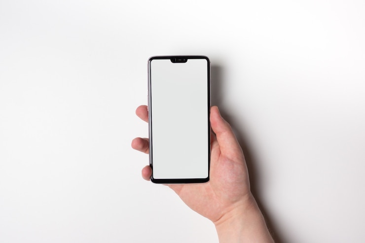 Un telefono con uno schermo bianco. Spazio libero sullo schermo. La mano tiene il telefono in verticale.