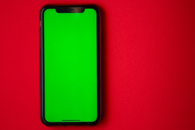 Un telefono con uno schermo verde è su una foto di alta qualità di sfondo rosso