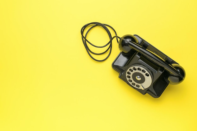 Un telefono nero retro su uno sfondo giallo la vecchia tecnica un posto per il tuo testo