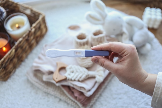 Un test di gravidanza positivo un giocattolo per bambini e una pila di cose Aspettando un bambino