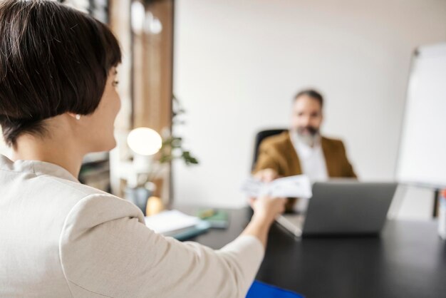 Un tirocinante sta dando una domanda di lavoro a un uomo d'affari mentre è seduto in ufficio