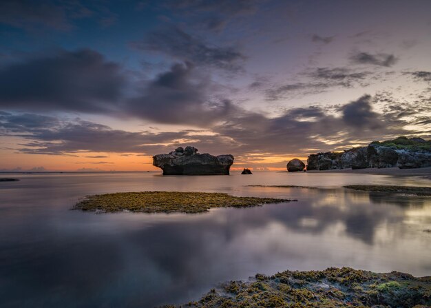 Un tramonto alla formazione rocciosa nell'acqua