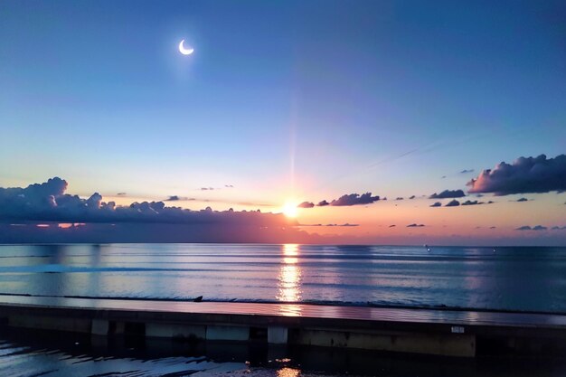 Un tramonto con la luna nel cielo