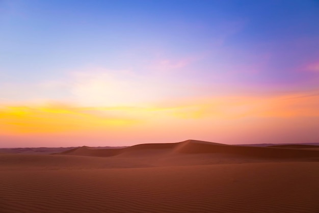 Un tramonto nel deserto con un cielo blu e un cielo viola e arancione.