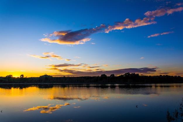 Un tramonto su un lago con un cielo azzurro e nuvole