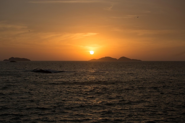 Un tramonto sull'oceano con una piccola isola sullo sfondo