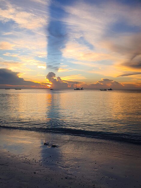 Un tramonto sulla spiaggia con una lunga nuvola nel cielo