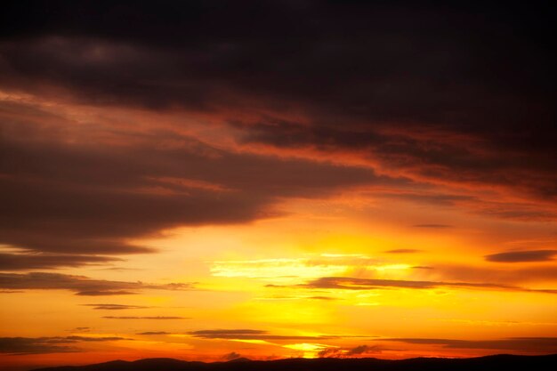 Un tramonto sulle montagne con il sole che tramonta dietro di esso.